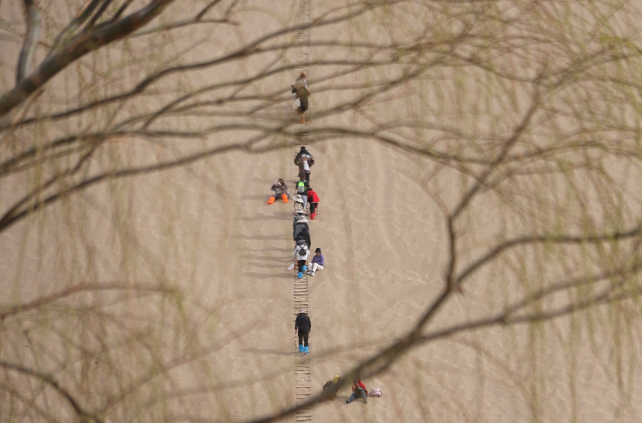 3月24日，游客在甘肅省敦煌市鳴沙山月牙泉景區(qū)游覽。張曉亮攝