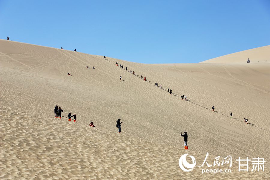 游客們在鳴沙山月牙泉景區(qū)內(nèi)游玩。人民網(wǎng)記者 王文嘉攝